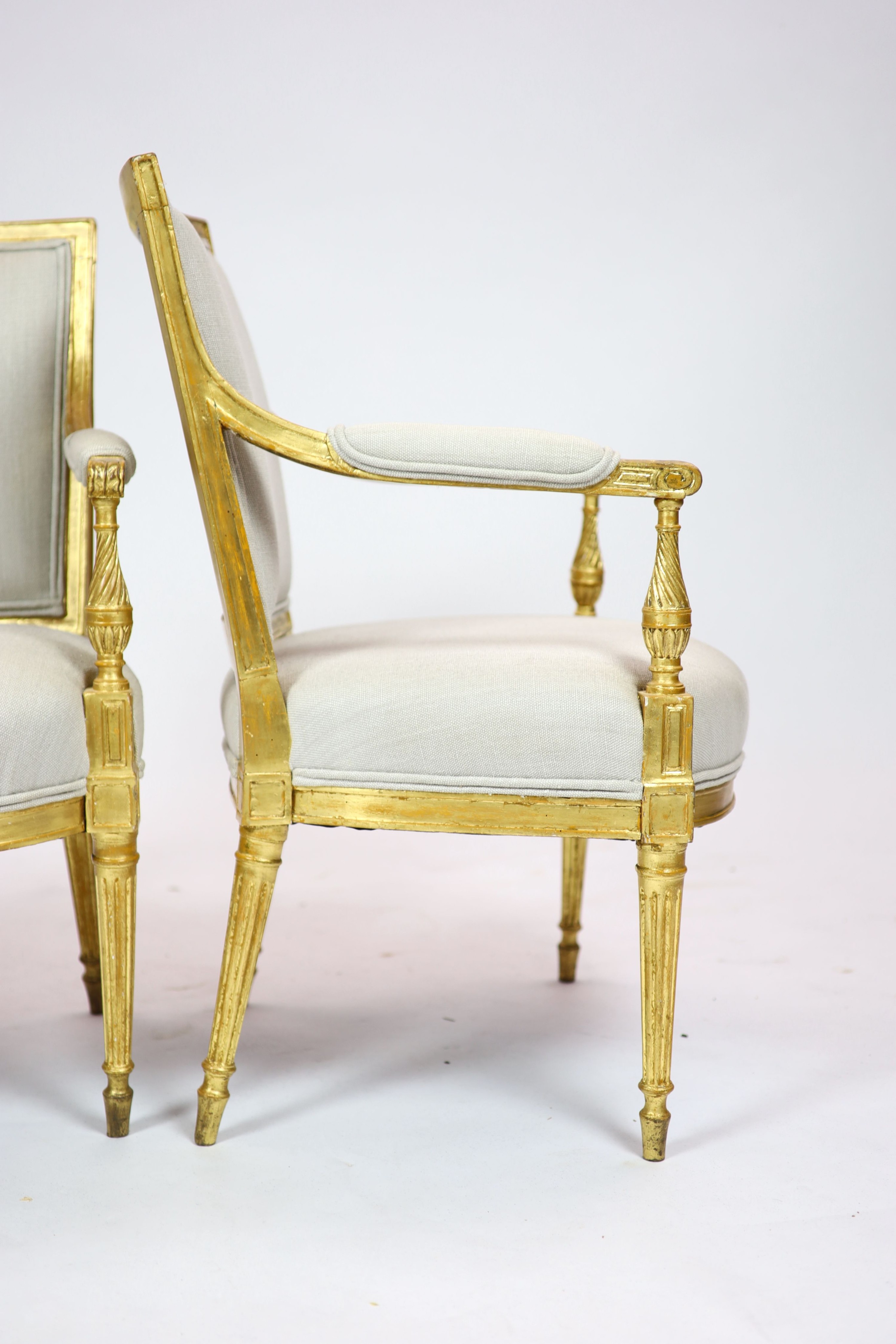 A pair of Louis XVI style giltwood elbow chairs H 89cm. W 59cm. D 60cm.